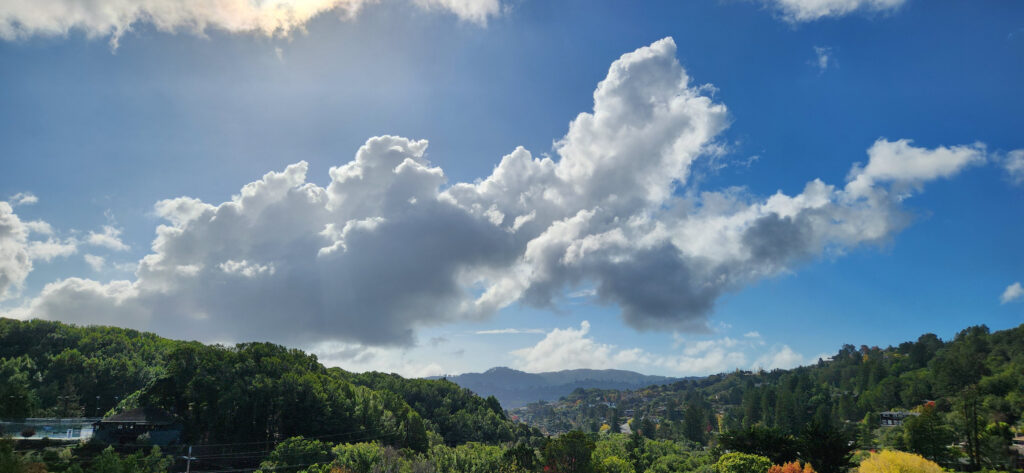 Lush green hills under a bright blue sky with fluffy clouds.